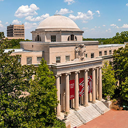 Mckissick Museum with garnet banners on between the large stone columns surrounded by trees on the historic Horseshoe. 