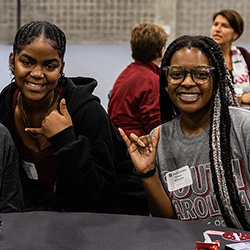 two students smiling and making the spurs up gesture at Imagine Carolina