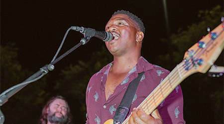 Person singing into a microphone playing the guitar. 