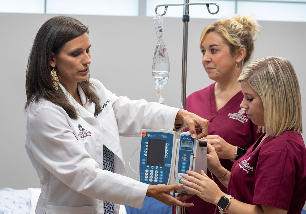 Nursing students with a professor around a piece of equipment. 