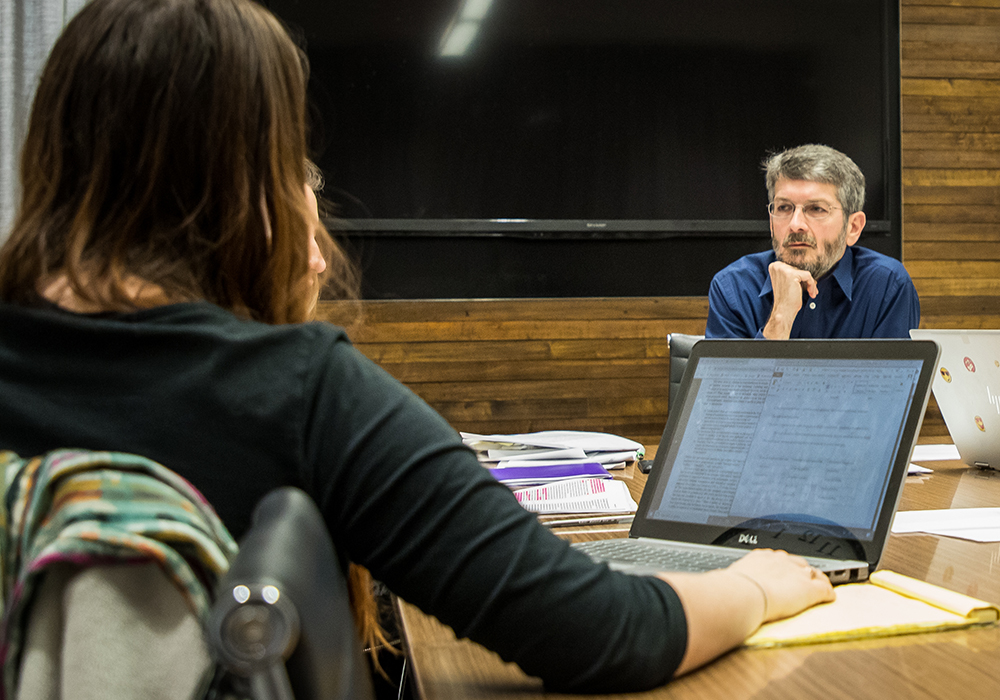 Professor talking to students at a table in a class.