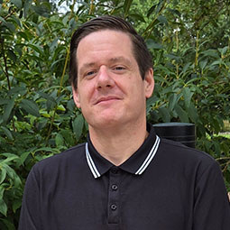 a man smiles in a black polo shirt with white rimmed color