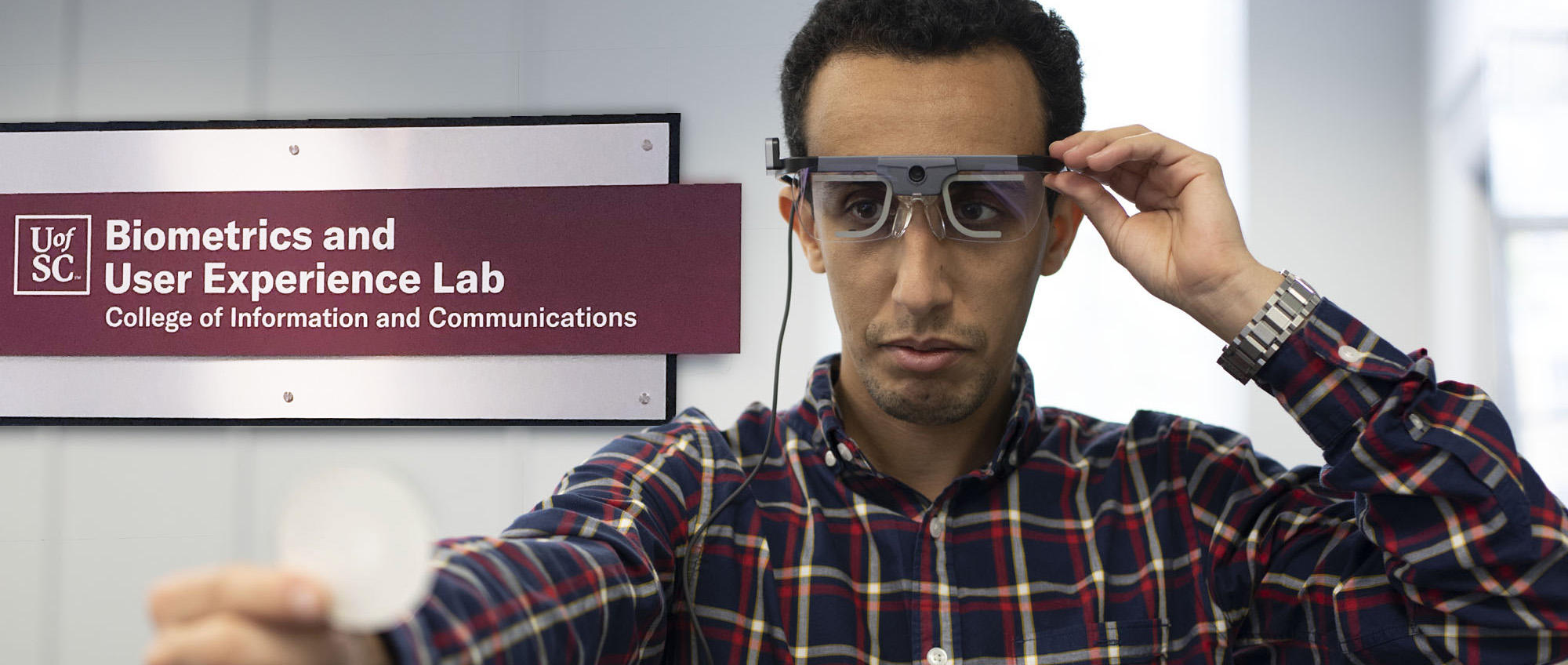 A male student inside the Baux Lab wearing the eyetracking software.