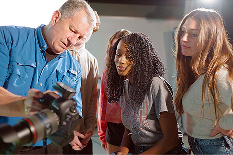 professor teaching students to use camera