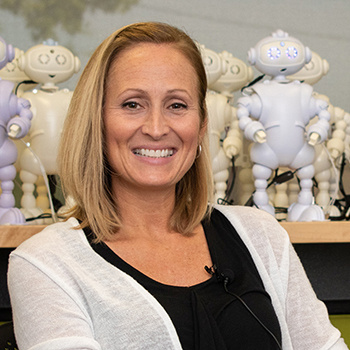 Laura Boccanfuso in front of shelf of small white robots