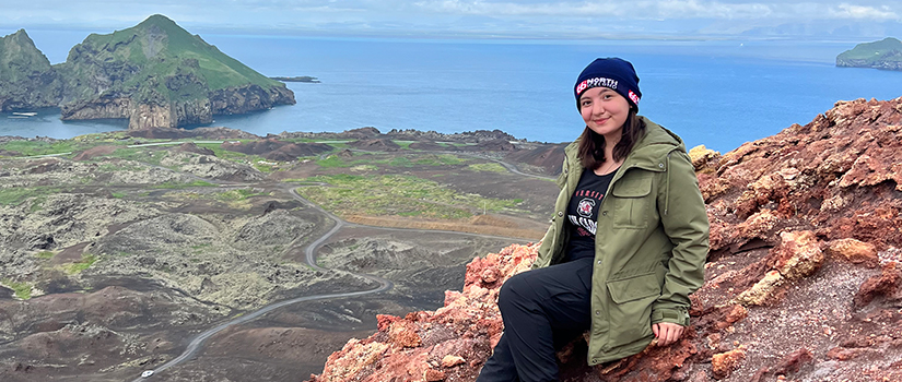 A student visiting Iceland poses on a hillside.