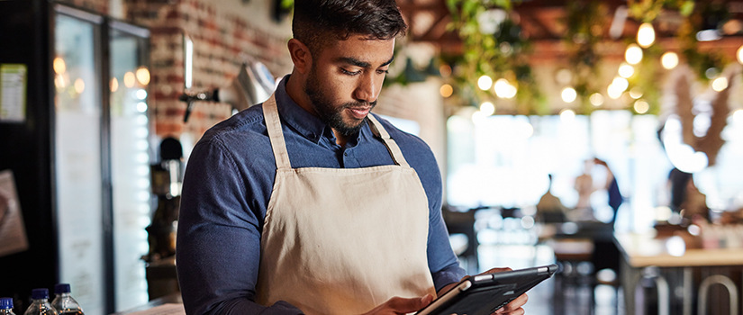 A food service worker looks at a tablet.