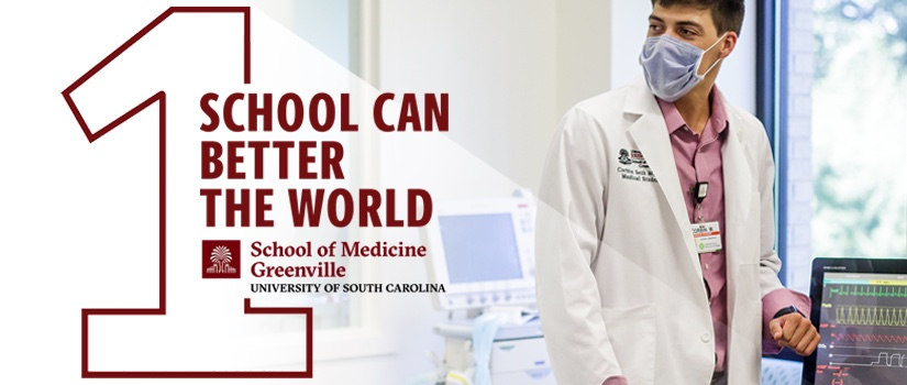 Male med student in white coats in sim lab. One school can better the world logo.