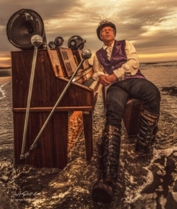 David Cutler sitting at piano in the ocean with steampunk theme