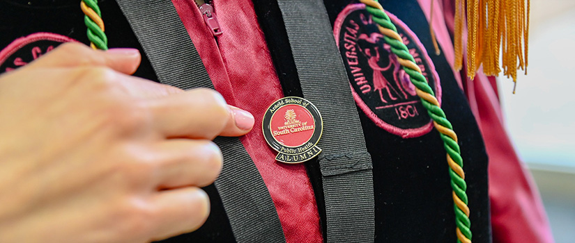 alumni pointing at alumni pin and tastles