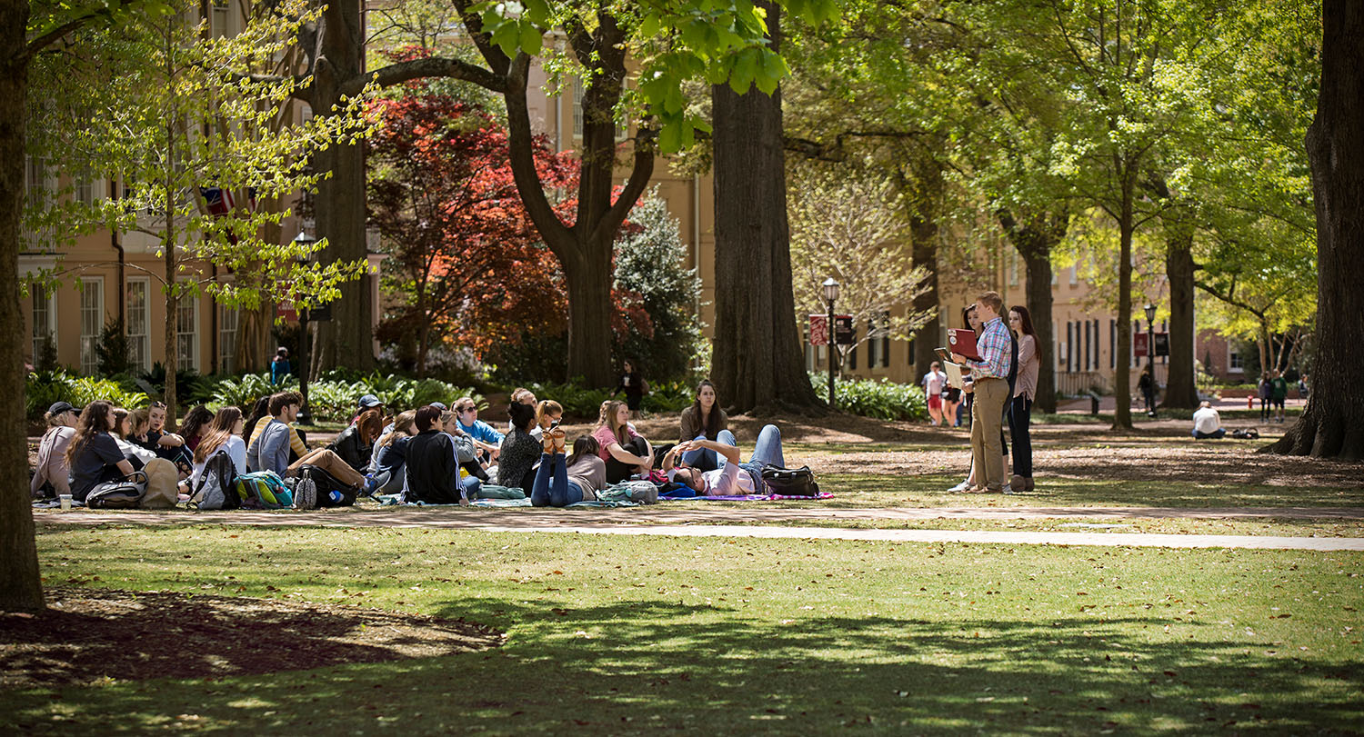 A group of students sits on the Horseshoe as part of a class held outside