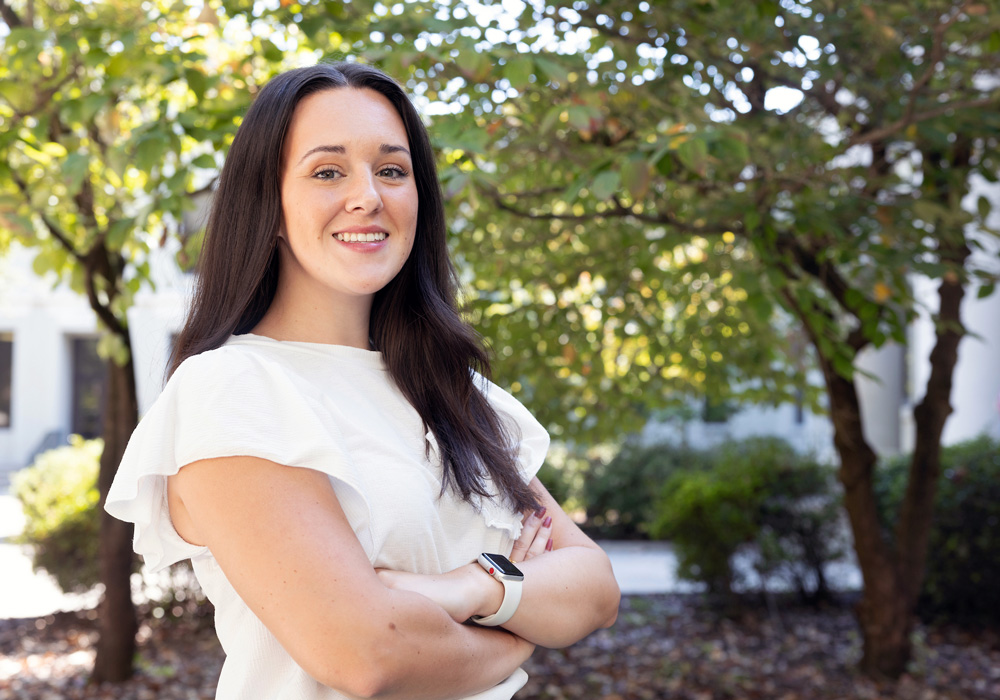 woman stands outside with greenery in the background