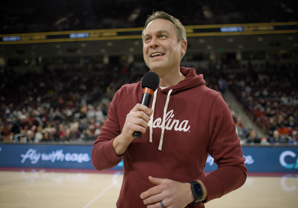 man holding a microphone stands in an arena