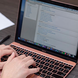 A set of hands hovers over a Mac keyboard