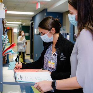 two women in masks work in a medical setting