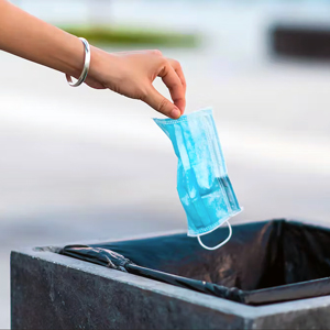 Hand wearing bracelet drops mask into trash can