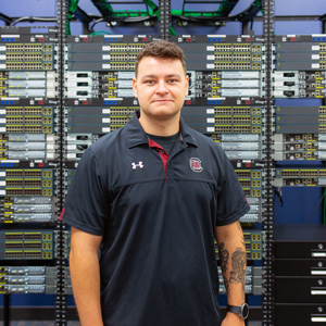 Man stands in front of a bank of computer servers