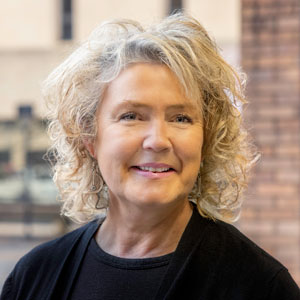 An environmental portrait of Lorie Donelle standing in front of the College of Nursing.