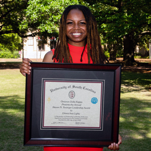 Ethena Inez Lighty stands on the horseshoe holding a large framed award