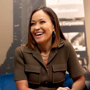 woman sits in front of a cityscape backdrop