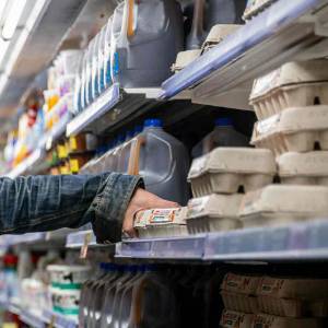 A supermarket customer reaches for a carton of eggs.