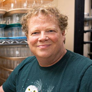 Jeff Dudycha smiles in front of glass beakers in his lab