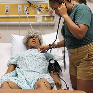 A young woman using a stethoscope on a training manikin